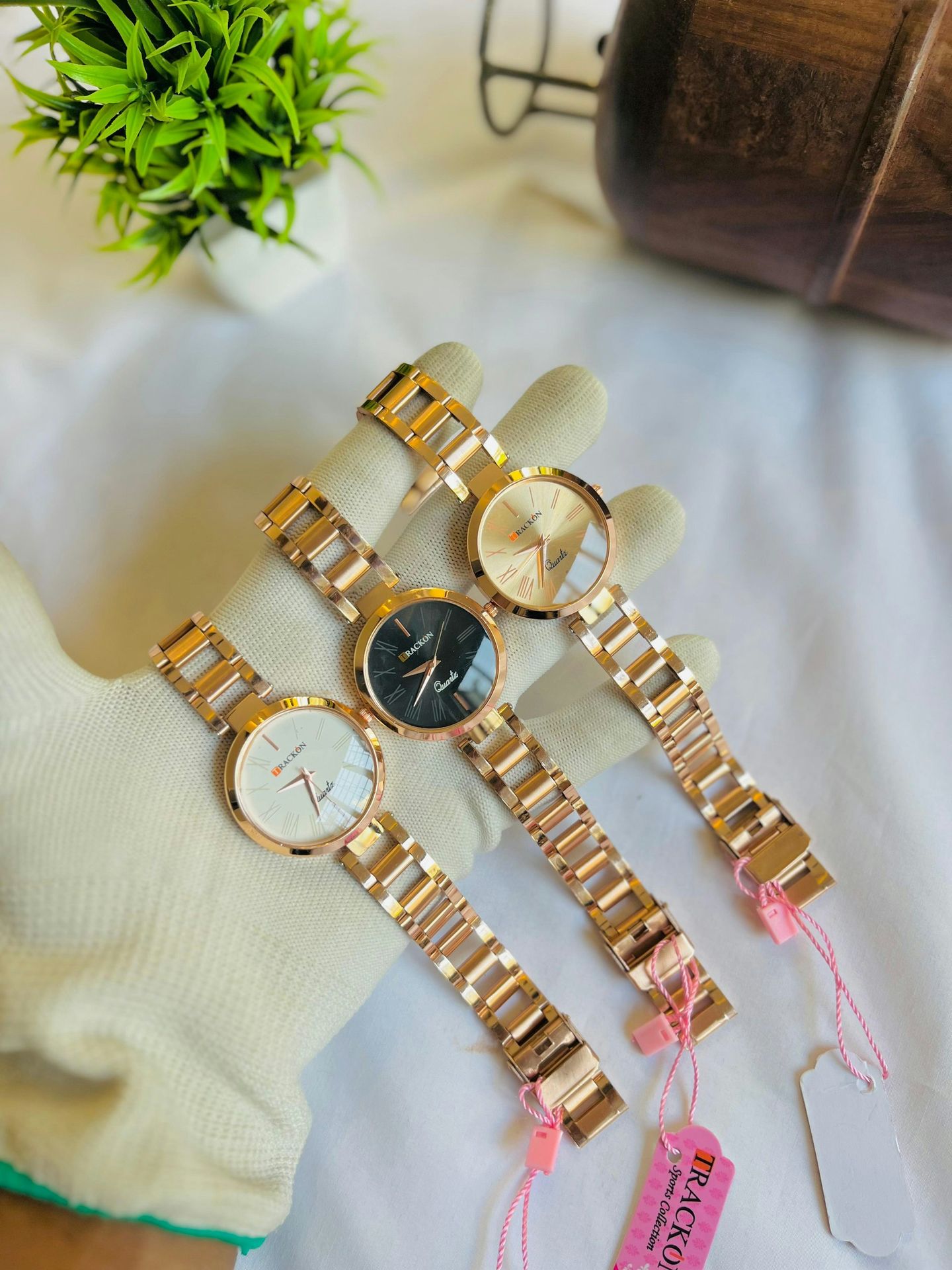 Three gold watches are presented on a white surface.